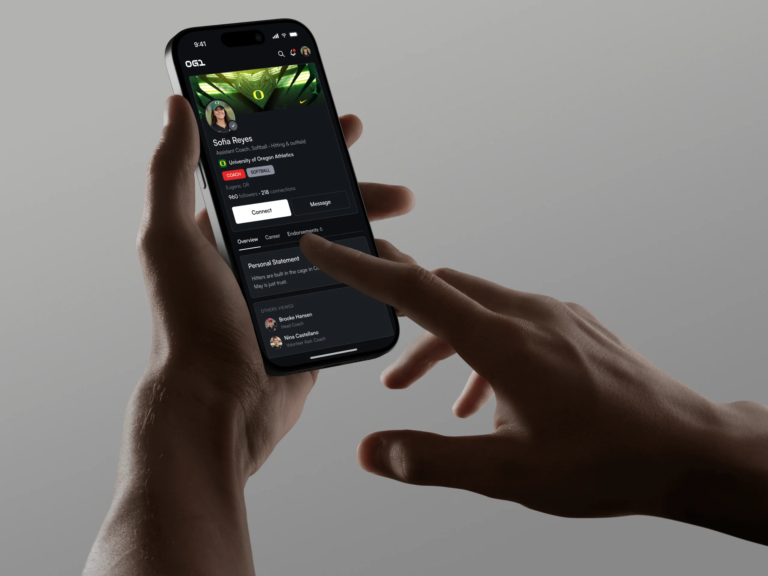 Hands hold a phone that shows a coach profile on OG1.