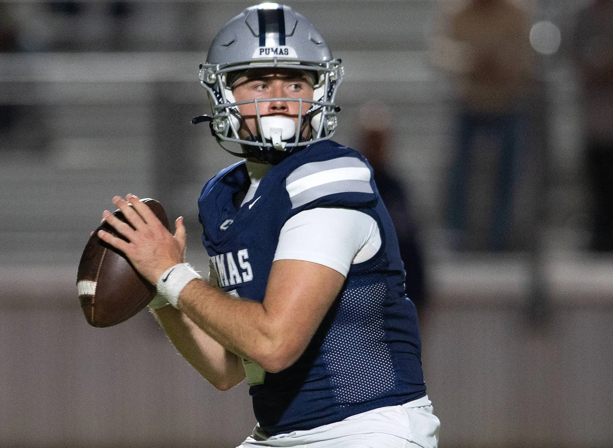A quarterback in a Pumas helmet and a navy jersey sets to throw.